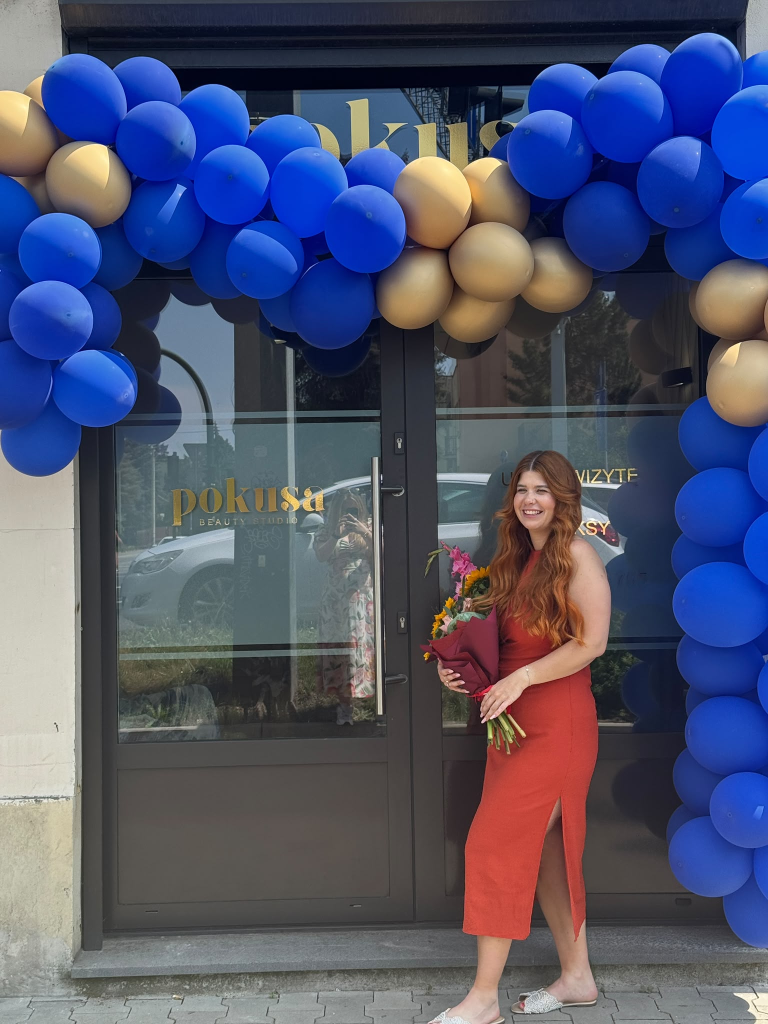 Aleksandra Pokusa z bukietem kwiatów przed salonem Pokusa Beauty Studio w Krakowie